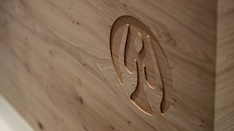 Schräger Blick auf das in die hölzerne Empfangstheke geschnitzte AllgäuHospiz-Logo in Holz